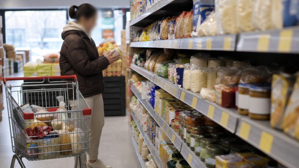 Покупатель у полки с товарами и акционными ценниками в продуктовом магазине